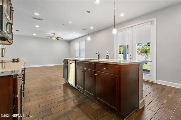 a kitchen with stainless steel appliances granite countertop a sink a stove and a wooden floors