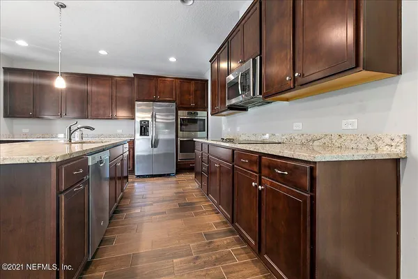 a kitchen with stainless steel appliances granite countertop a sink a stove and a refrigerator