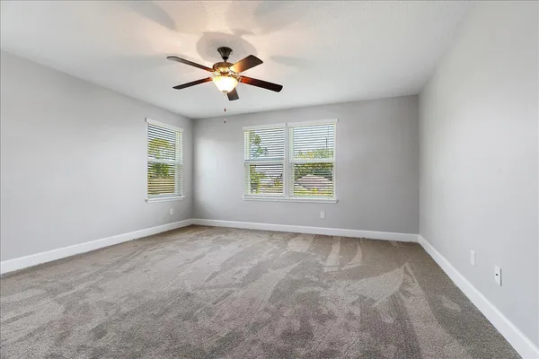an empty room with windows and fan