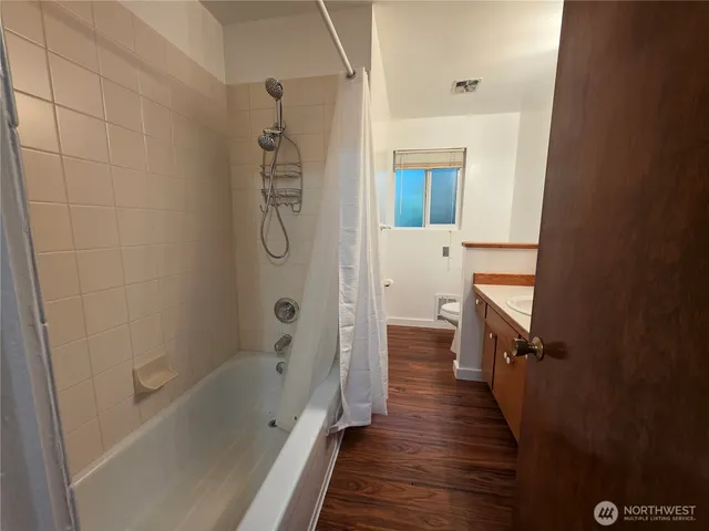 a bathroom with a bathtub a sink and wooden floor