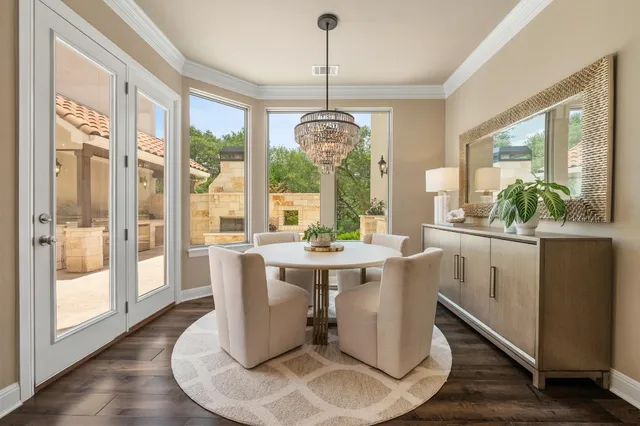 a dining room with wooden floor a chandelier a glass table and chairs