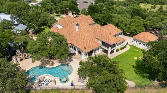 a view of a big house with a big yard and large trees