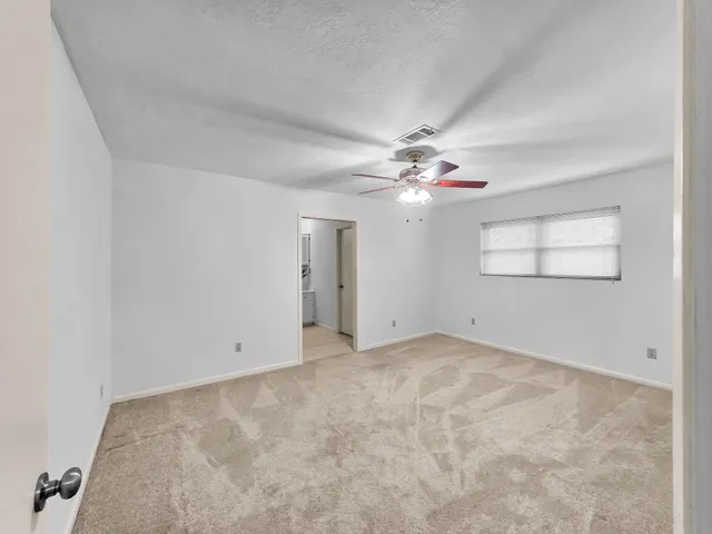 an empty room with chandelier fan and windows
