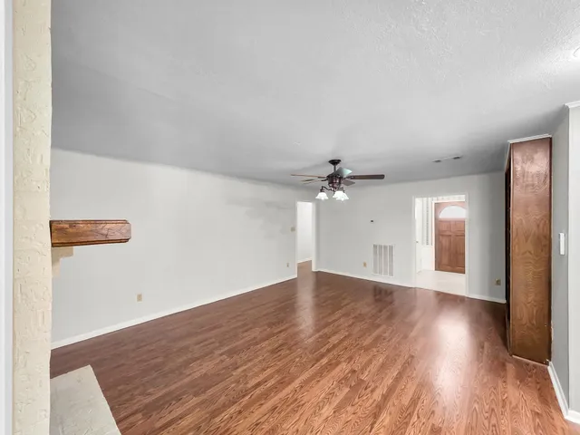 a view of an empty room with wooden floor fireplace and a window