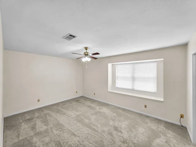 an empty room with a window and a ceiling fan