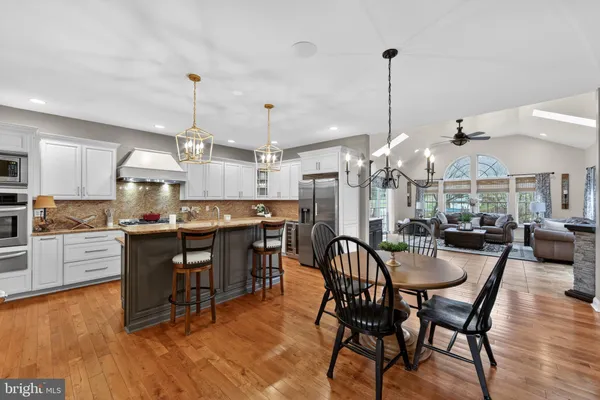 a kitchen with stainless steel appliances kitchen island granite countertop a table chairs and a chandelier