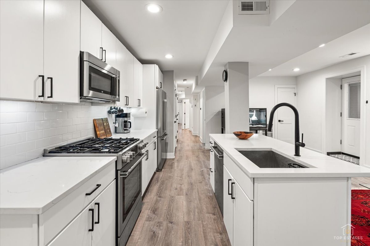 3432 West Belden Avenue, Unit G Chicago, IL 60647 - Photo 13 of 32 a kitchen with stainless steel appliances granite countertop a sink stove top oven and refrigerator