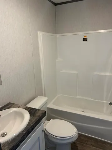 a bathroom with a granite countertop bathtub shower sink vanity and toilet