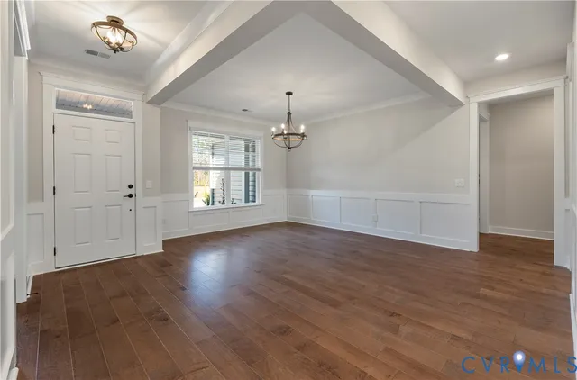 an empty room with wooden floor chandelier and windows