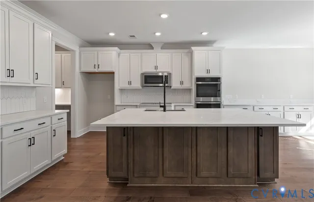 a kitchen with kitchen island a sink stainless steel appliances and cabinets