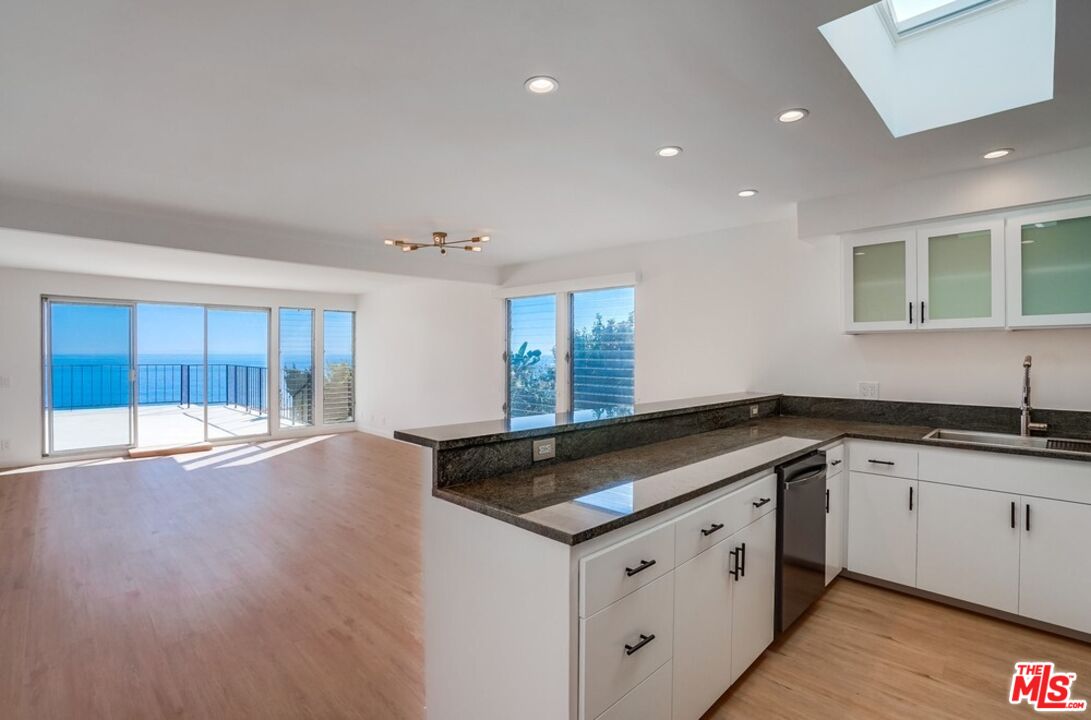 18241 Coastline Drive, Unit 2 Malibu, CA 90265 - Photo 18 of 45 a kitchen with granite countertop a sink and dishwasher with wooden floor