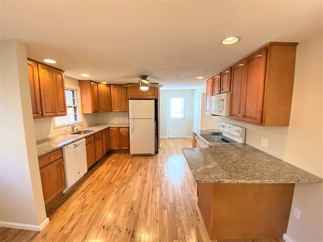 a large kitchen with cabinets wooden floor and stainless steel appliances