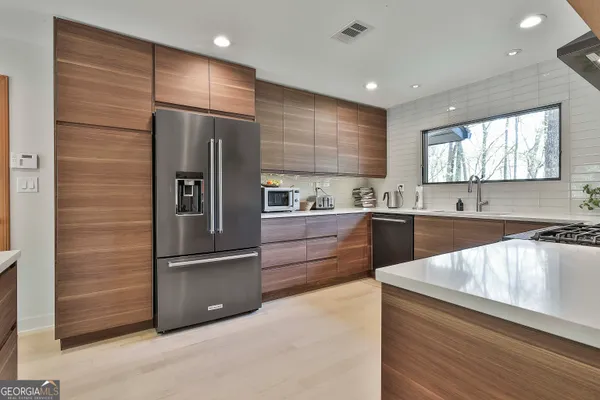 a kitchen with stainless steel appliances granite countertop a refrigerator a sink and a stove top oven