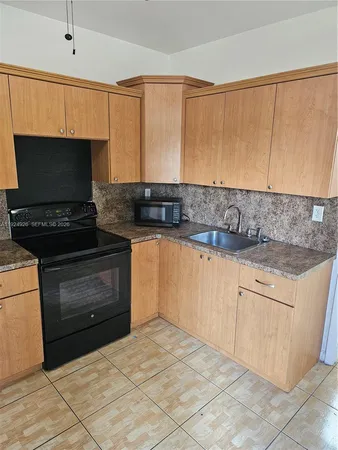 a kitchen with granite countertop a sink a stove top oven and cabinets