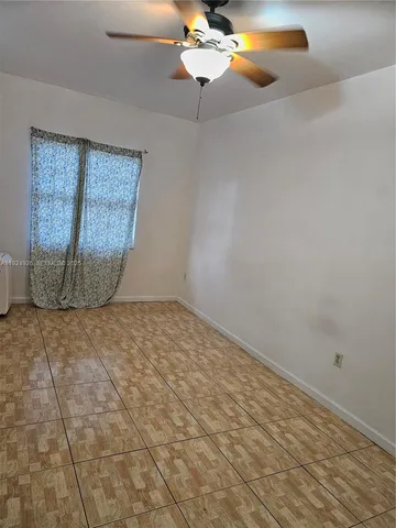 an empty room with a chandelier fan and wooden floor