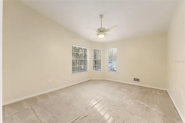 an empty room with windows and fan