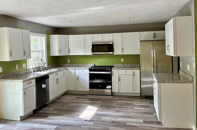 a kitchen with stainless steel appliances granite countertop a refrigerator sink and stove