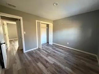 an empty room with wooden floor and a bathroom