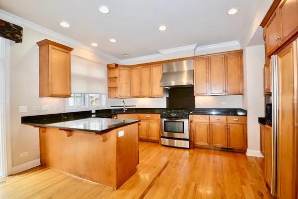 a kitchen with stainless steel appliances granite countertop a sink a stove and a refrigerator