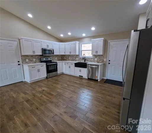 a kitchen with kitchen island a sink a stove a refrigerator and cabinets