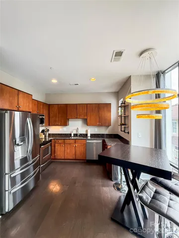 a kitchen with stainless steel appliances a stove a sink a microwave a dining table and chairs with wooden floor