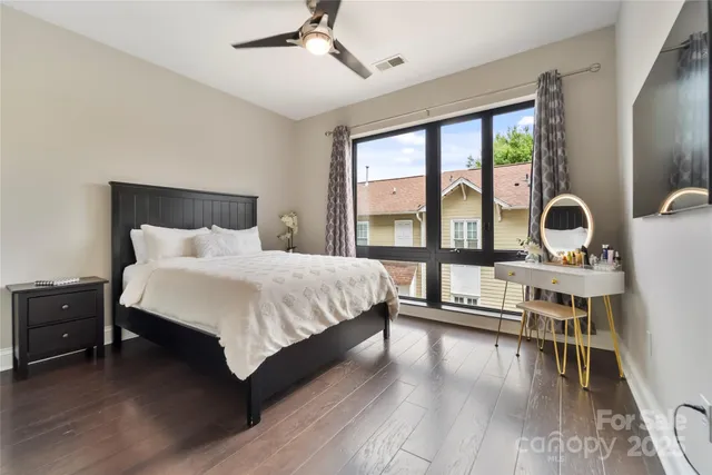 a bedroom with a bed a table and three large window