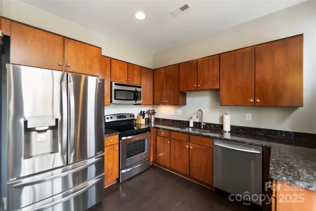 a kitchen with granite countertop stainless steel appliances and wooden cabinets