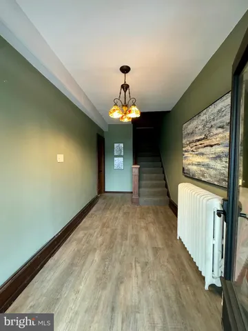 a view of a hallway with wooden floor and chandelier