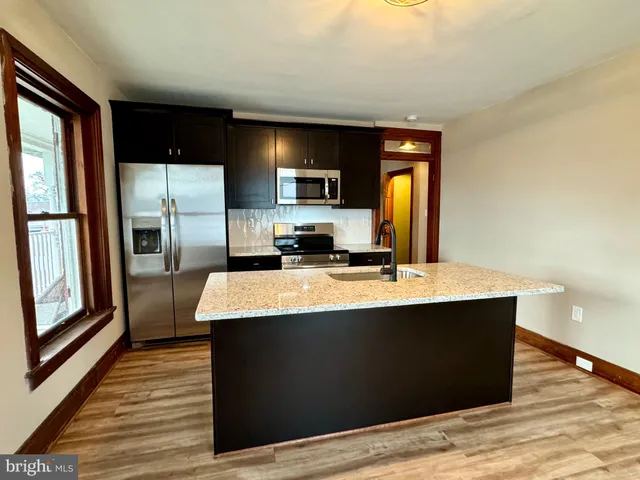 a kitchen with kitchen island a counter top space cabinets and stainless steel appliances