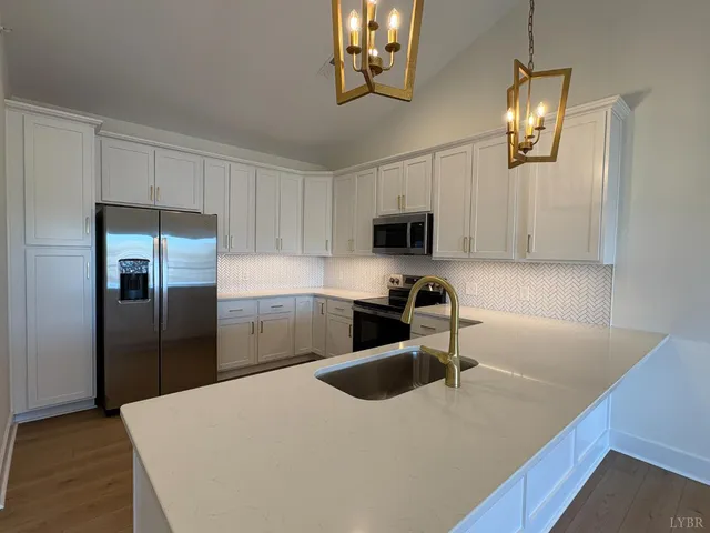 a kitchen with stainless steel appliances granite countertop a sink a stove a refrigerator a microwave oven with white cabinets and wooden floor