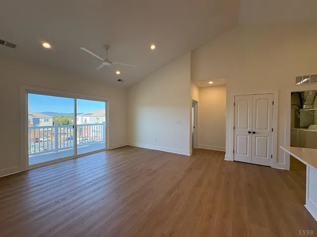 a view of an empty room with a window and wooden floor
