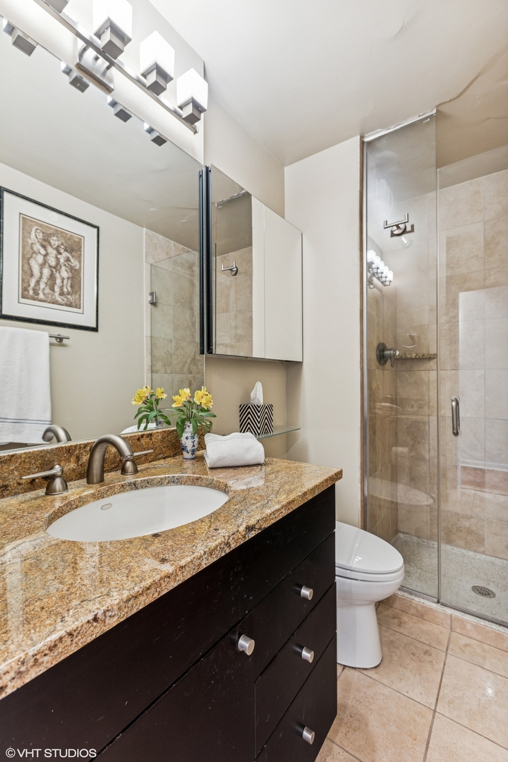 71 East Division Street, Unit 1606 Chicago, IL 60611 - Photo 21 of 34 a bathroom with a granite countertop sink a toilet a mirror and shower