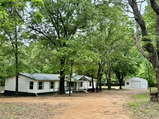 a view of a white house that has a tree in front of it