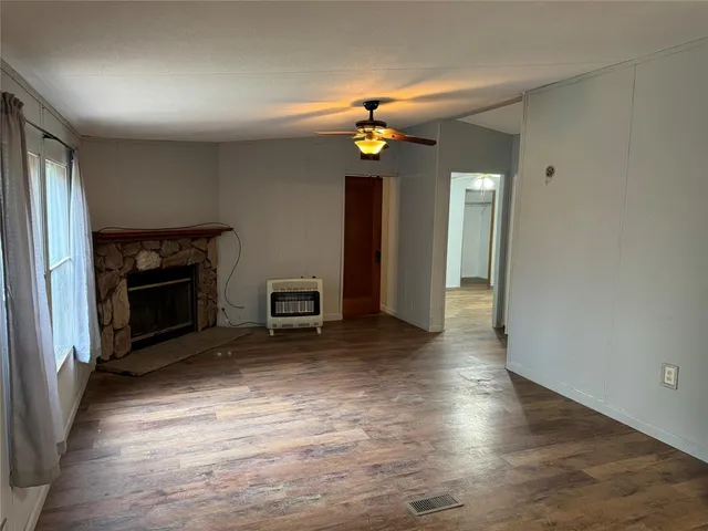 an empty room with wooden floor fireplace and a window