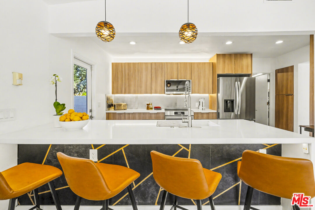 37223 Ferber Drive Rancho Mirage, CA 92270 - Photo 15 of 48 a kitchen with stainless steel appliances kitchen island granite countertop a dining table chairs and a refrigerator