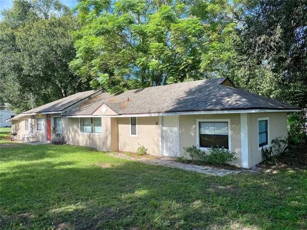 a view of a house with a yard and potted plants