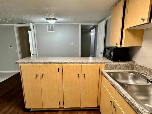 a view of a kitchen with kitchen island a sink wooden floor and a large window