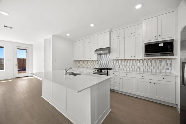a kitchen with white cabinets appliances and sink