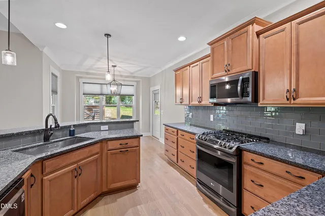 a kitchen with stainless steel appliances granite countertop a sink stove and microwave