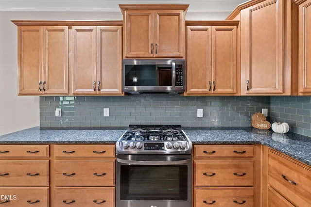a kitchen with granite countertop stainless steel appliances white cabinets granite counter tops and a wooden floors