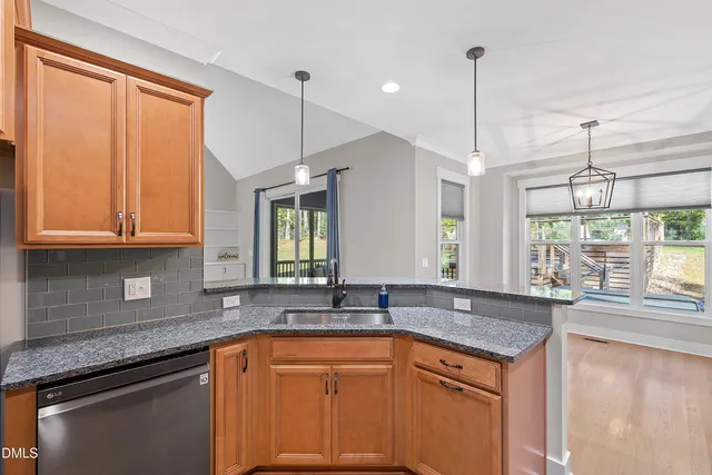 a kitchen with stainless steel appliances granite countertop a sink a counter space and a window