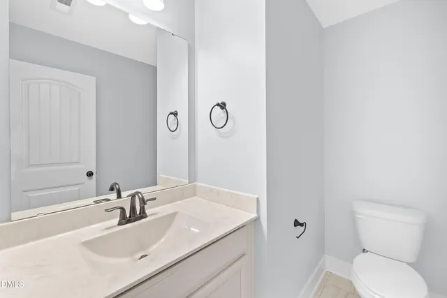 a bathroom with a granite countertop sink toilet and a mirror