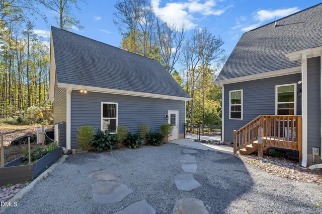 a view of a house with a yard and floor to ceiling window and potted plants