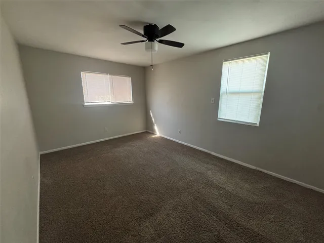 an empty room with a window and a ceiling fan