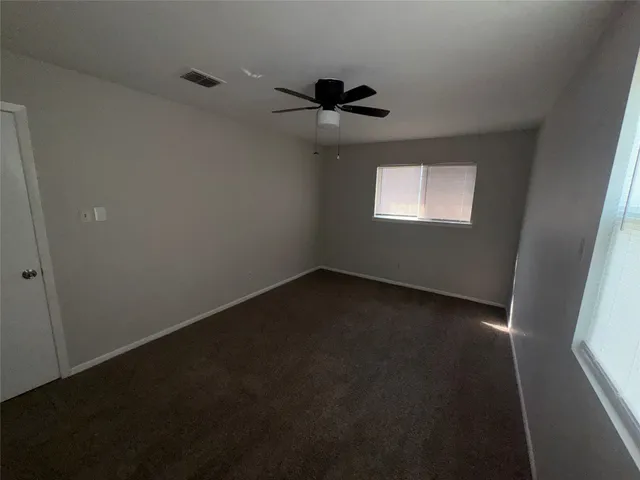 an empty room with a window and a fan