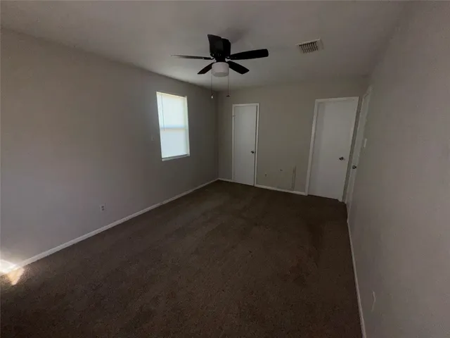 an empty room with wooden floor and ceiling fan