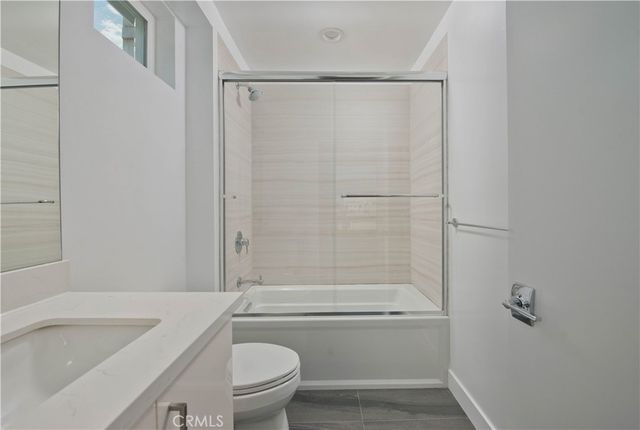 a bathroom with a granite countertop bathtub shower sink vanity and toilet