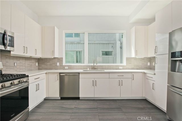 a large white kitchen with granite countertop a stove and a sink