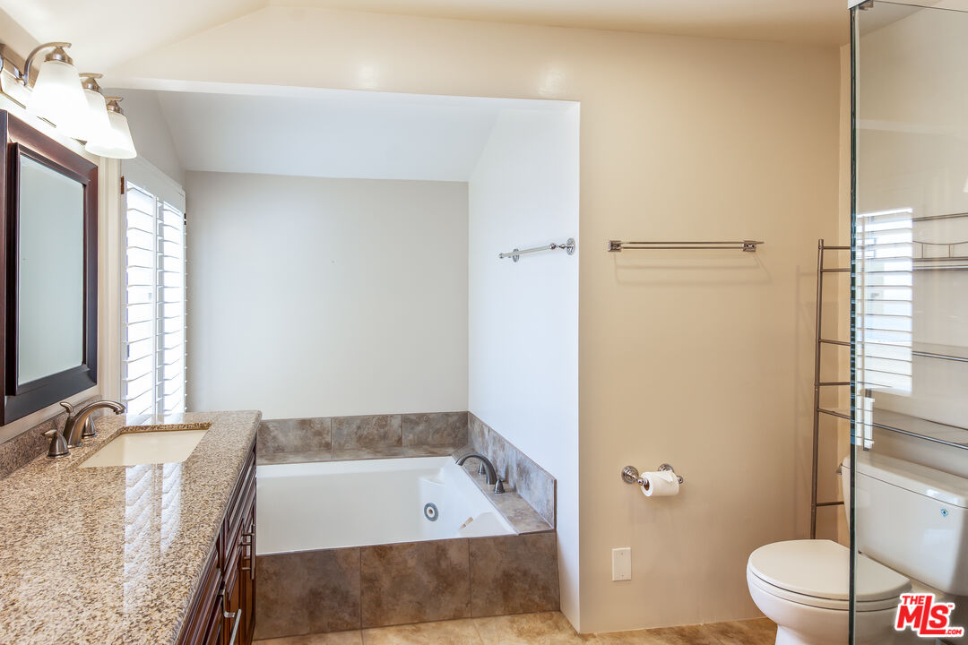 18057 Coastline Drive, Unit 5 Malibu, CA 90265 - Photo 13 of 20 a bathroom with a granite countertop sink a toilet a mirror and shower