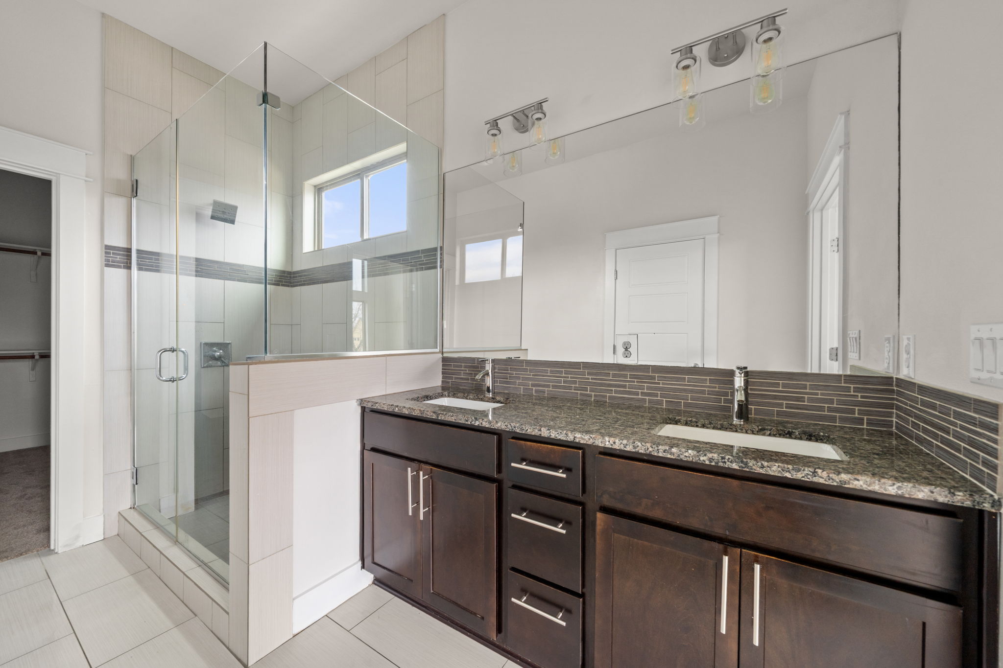 1160 Nickols Avenue, Unit A Austin, TX 78721 - Photo 26 of 40 Bathroom featuring double vanity, a stall shower, a spacious closet, decorative backsplash, and light tile patterned floors